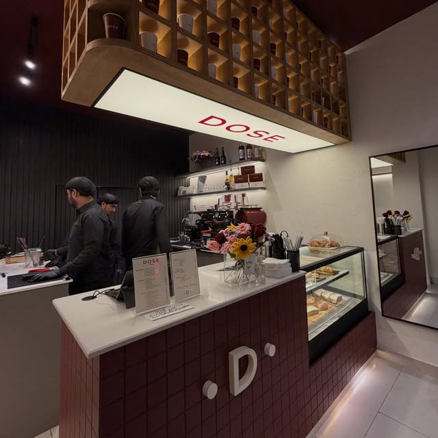 Cafe counter with a lit panel reading DOSE in red.